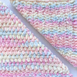 KnitPal Chenillique XL chenille yarn in Pastel Dreams, close-up swatch half knit half crochet showing plush pink, blue, and cream texture