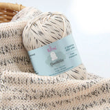 KnitPal GentleBliss DK weight yarn in black and cream marl, skein on knitted fabric swatch, label visible