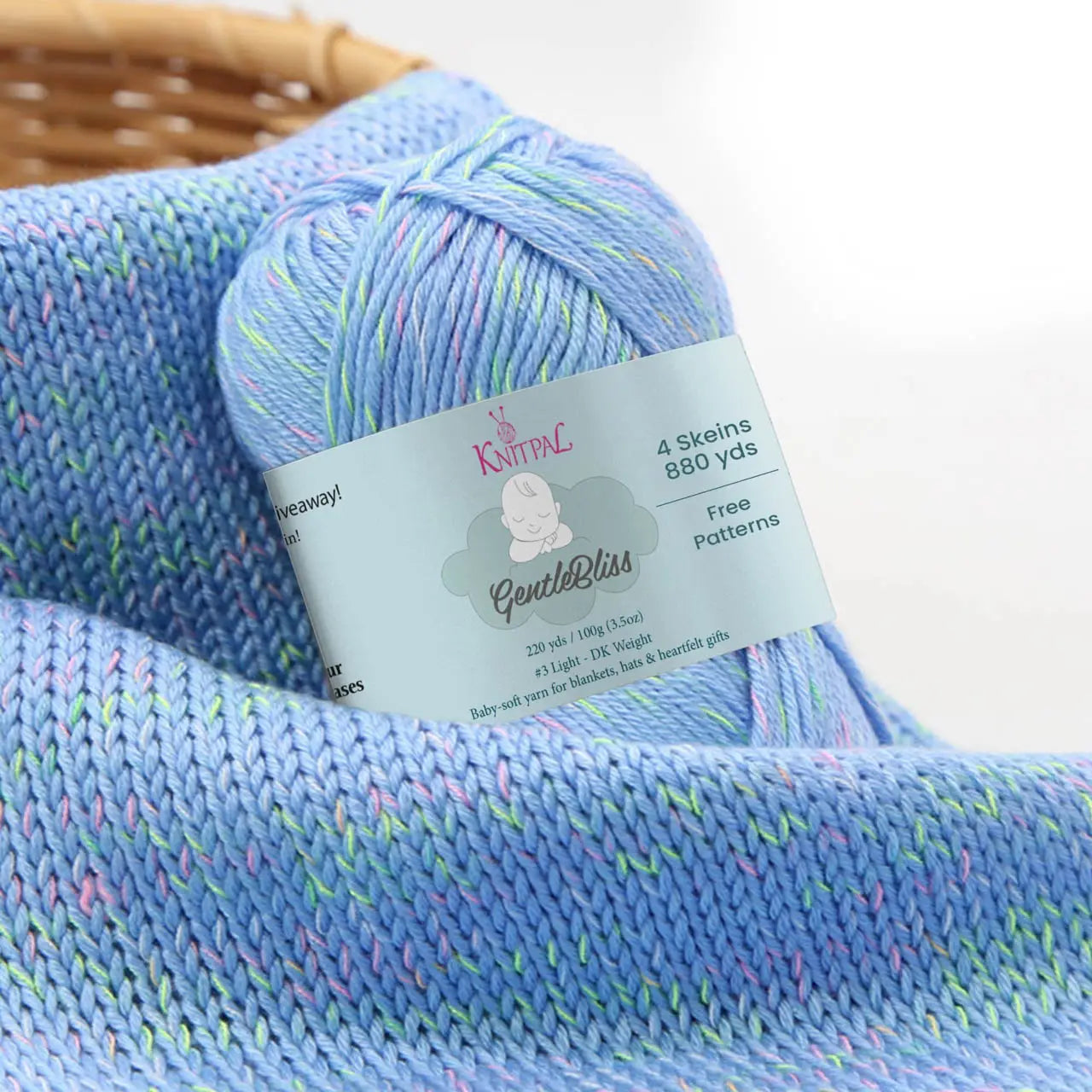 KnitPal GentleBliss DK weight yarn in cornflower blue with soft pastel marl flecks, skein on knitted fabric swatch, label visible