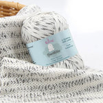 KnitPal GentleBliss DK weight yarn in white with black marl twists, skein on knitted fabric swatch, label visible