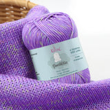 KnitPal GentleBliss DK weight yarn in bright lavender purple with multicolor marl flecks, skein on knitted fabric swatch, label visible