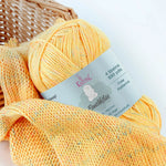 KnitPal GentleBliss DK weight yarn in soft sunny yellow with multicolor marl flecks, skein on knitted fabric swatch, label visible