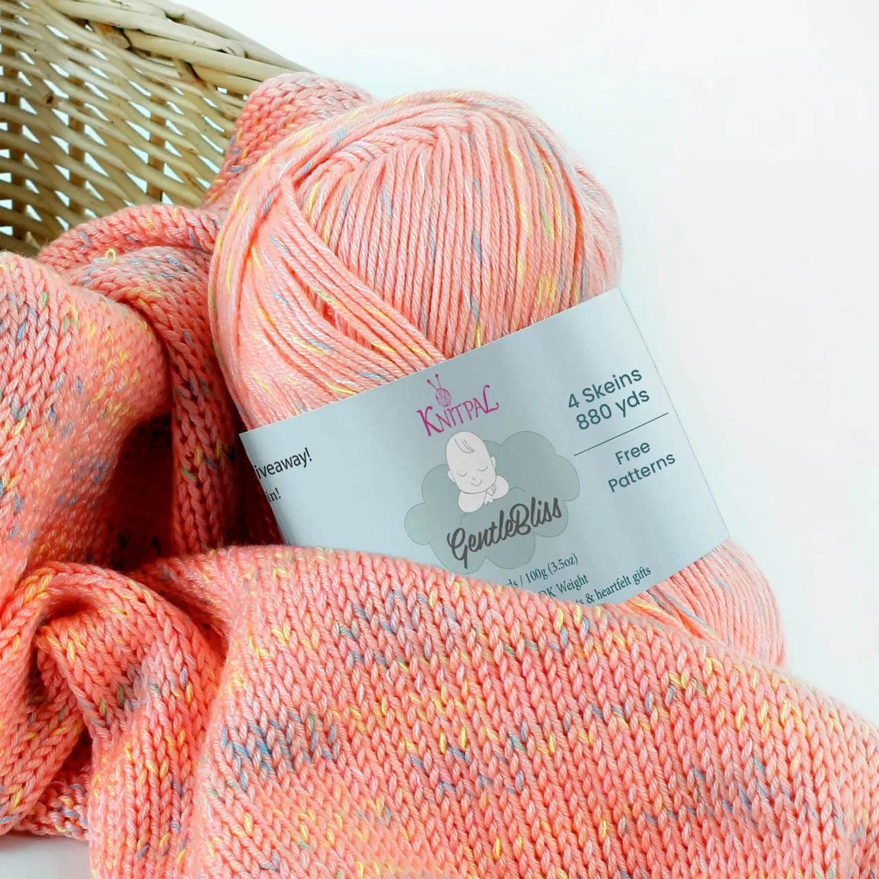 KnitPal GentleBliss DK weight yarn in warm coral peach with multicolor marl flecks, skein on knitted fabric swatch, label visible