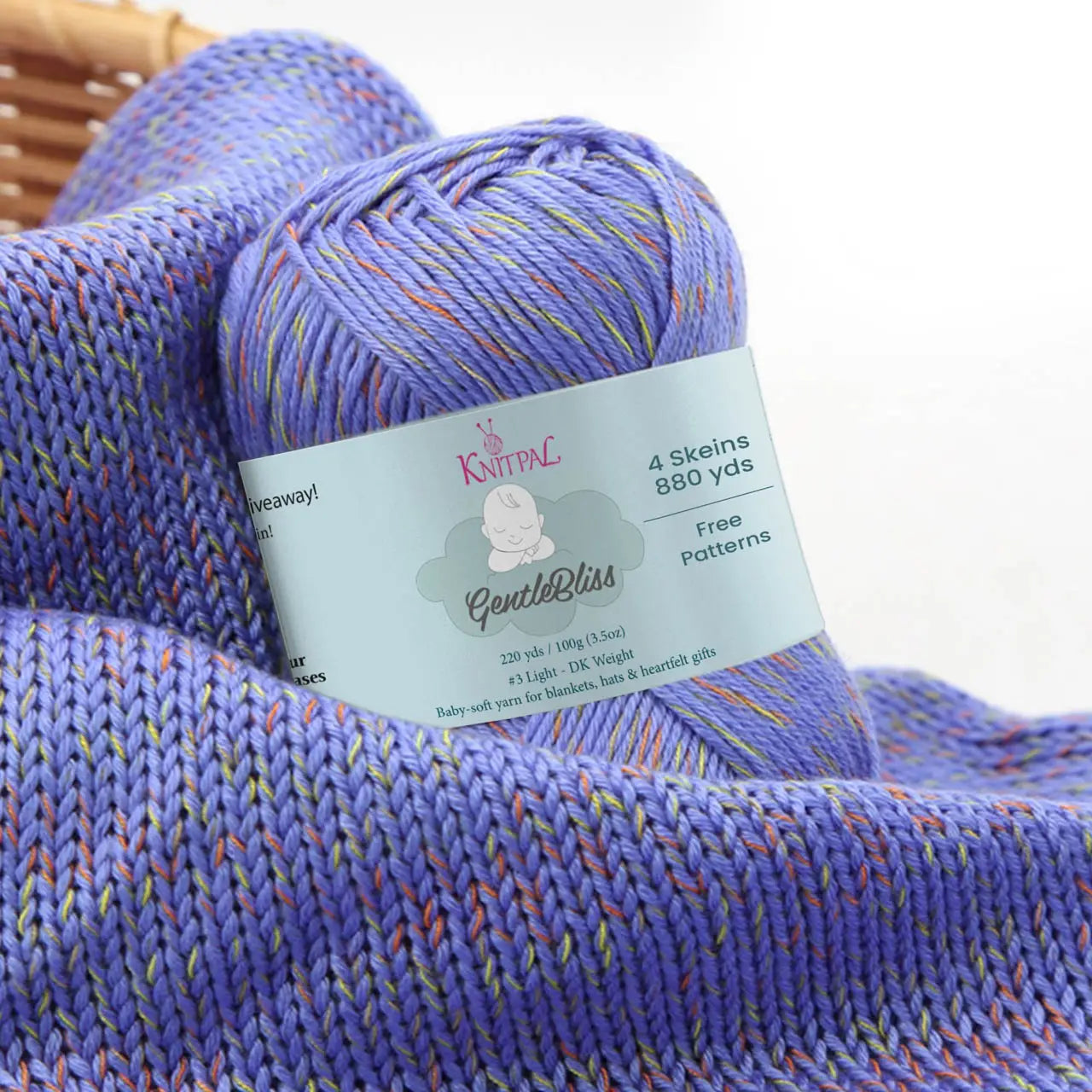 KnitPal GentleBliss DK weight yarn in vibrant periwinkle purple with orange and yellow-green marl flecks, skein on knitted fabric swatch, label visible