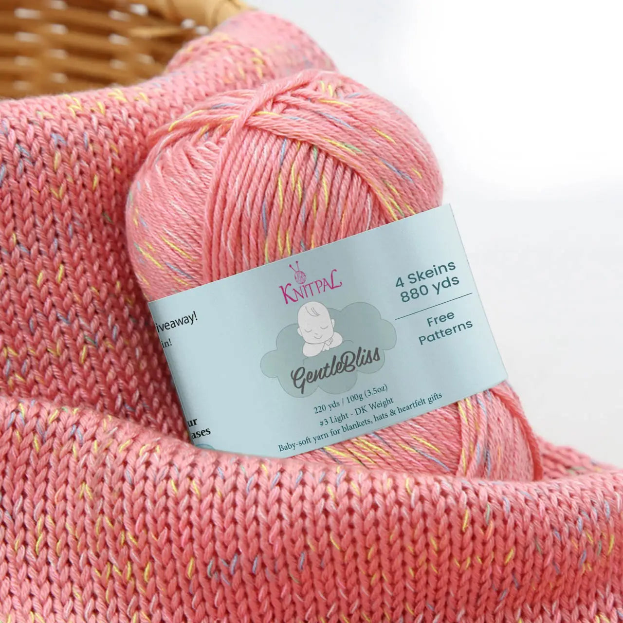 KnitPal GentleBliss DK weight yarn in fresh coral pink with multicolor marl flecks, skein on knitted fabric swatch, label visible