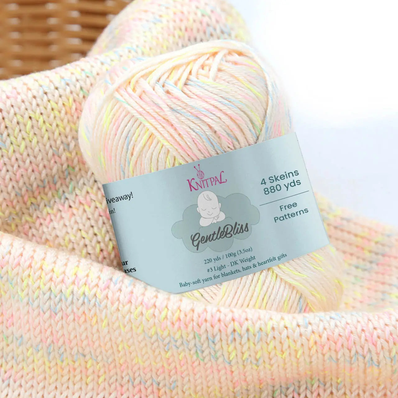 KnitPal GentleBliss DK weight yarn in warm cream with soft pastel multicolor marl flecks, skein on knitted fabric swatch, label visible