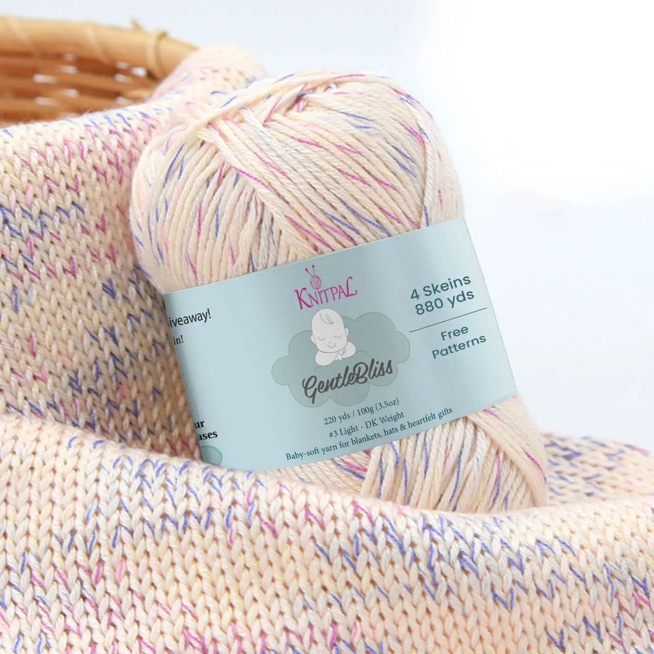 KnitPal GentleBliss DK weight yarn in soft vanilla cream with pink and purple marl flecks, skein on knitted fabric swatch, label visible