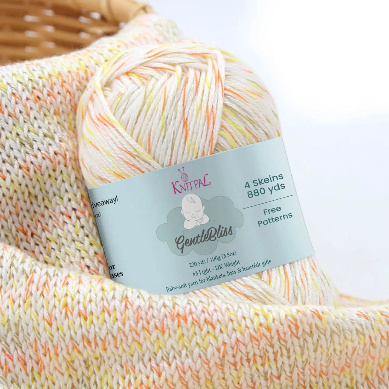 KnitPal GentleBliss DK weight yarn in creamy white with orange and yellow marl flecks, skein on knitted fabric swatch, label visible