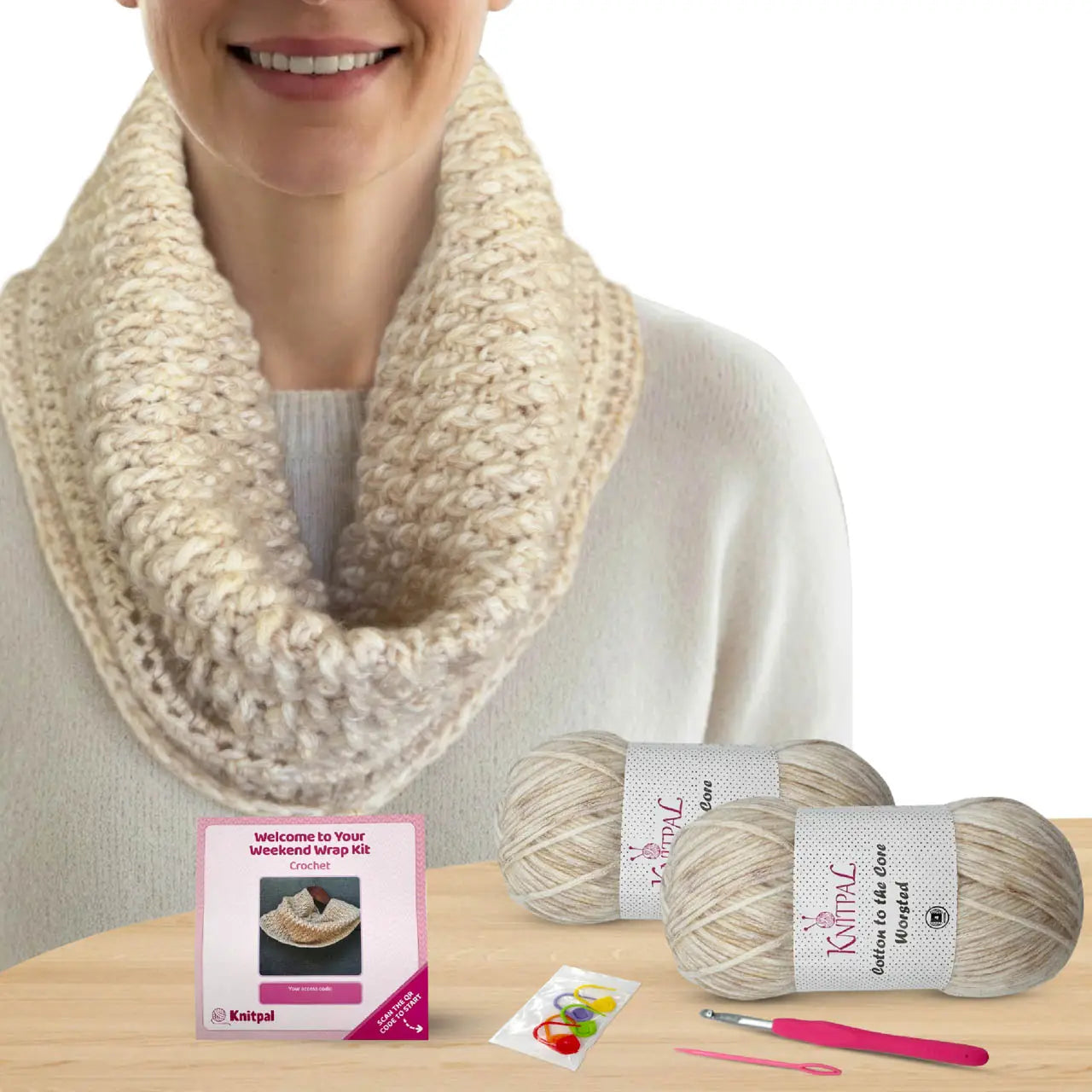 Person wearing a knitted scarf with yarn, needles, and packaging on a table